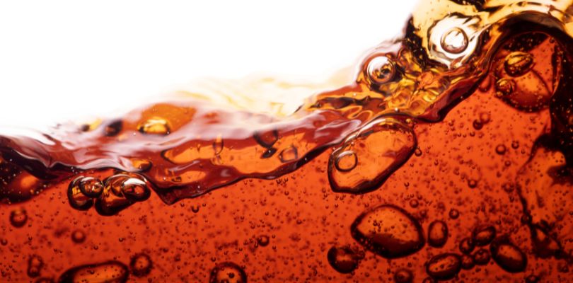 Dark brown soda flowing over a white background.