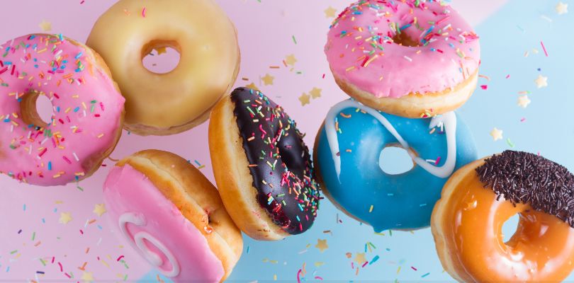 A variety of doughnuts on a pink and blue background.