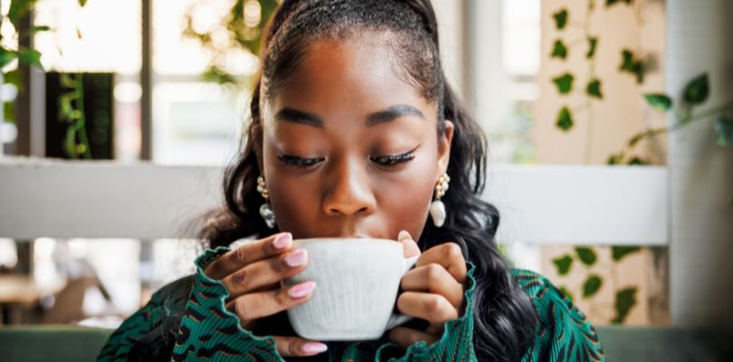 A woman drinking coffee out of mug.